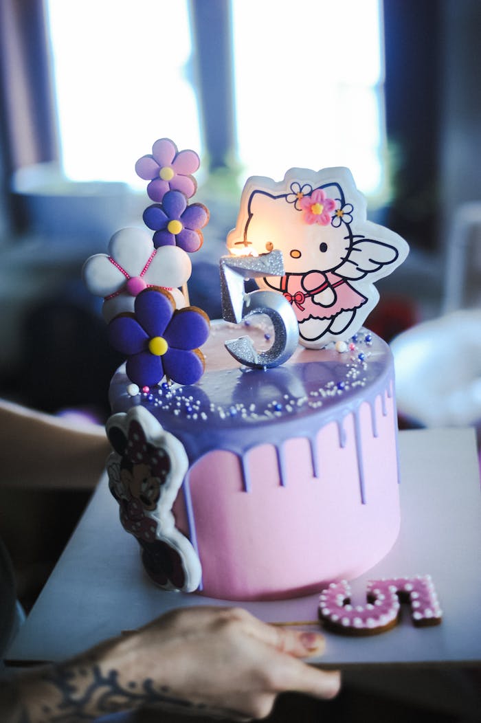 A vibrant 5th birthday cake featuring a cute kitty design and decorative flowers, perfect for celebrations.